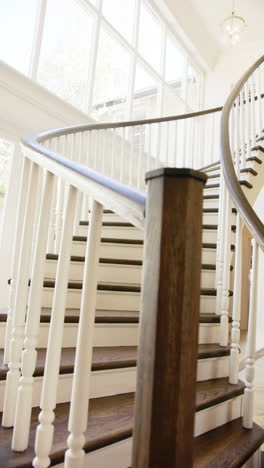 vertical video: curved staircase with wooden handrail in modern, bright home interior