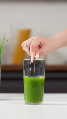 colocando una paja en un jugo de pasto de trigo verde vibrante en un mostrador de cocina moderno