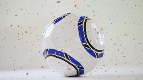 Animation-of-gold-confetti-falling-over-soccer-ball