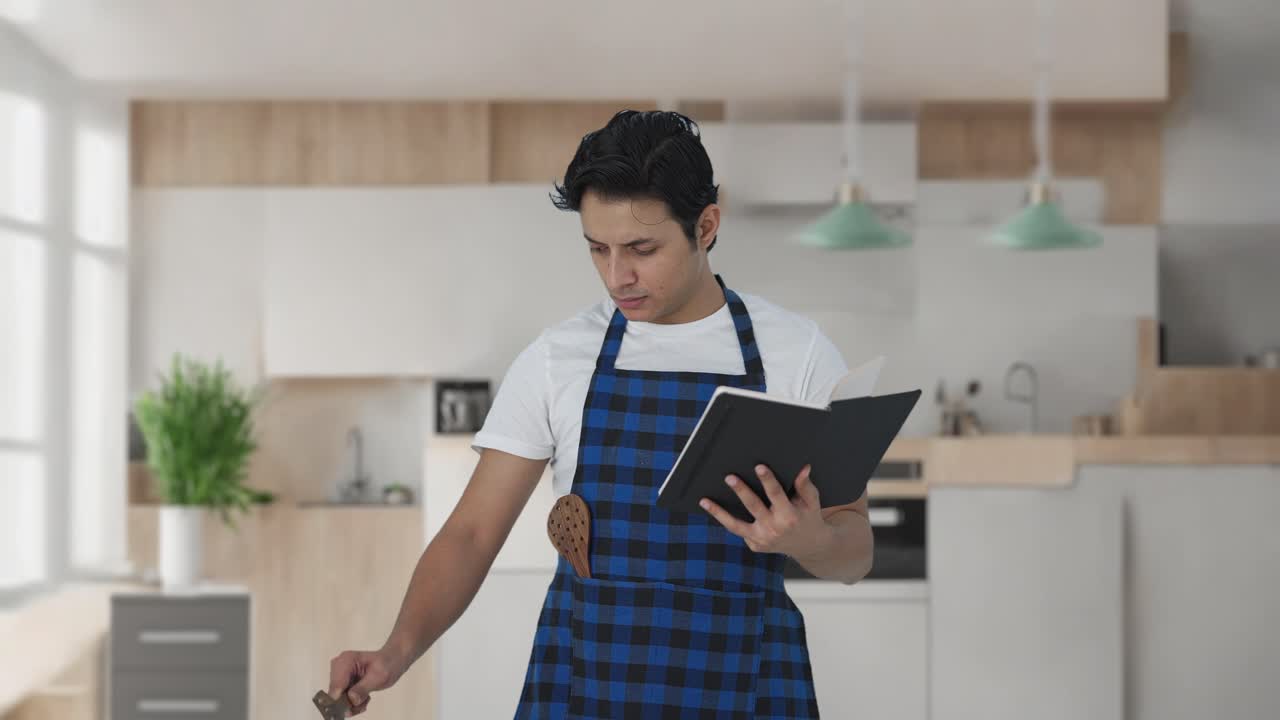 cocinero indio serio haciendo comida de un libro de recetas
