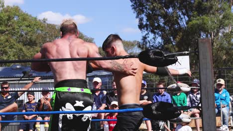 dos luchadores compiten en un ring al aire libre ante la audiencia.