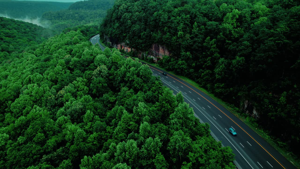 Drone aerial of red semi truck hauling freight on Monteagle Tennessee mountain pass, symbolizing supply chain, travel, and commerce