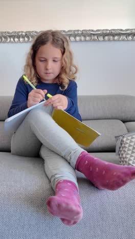 girl writing in a notebook on a sofa