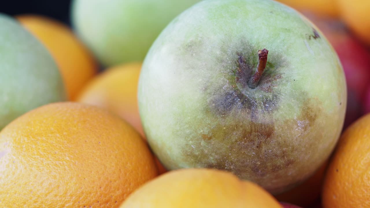 Close-up of a Green Apple among Oranges