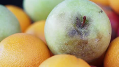 close-up of a green apple among oranges