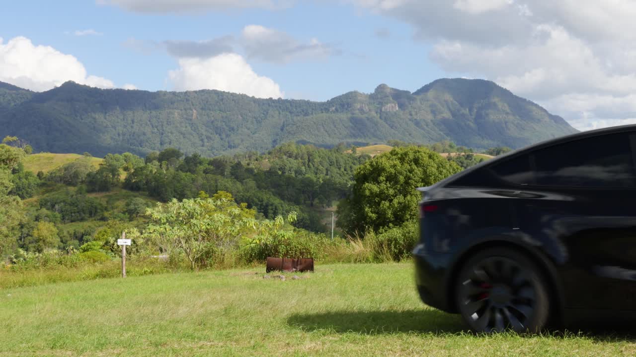 검은 차가 그림 같은 산을 배경으로 움직인다