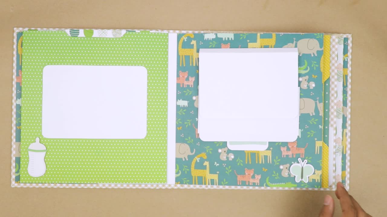 Open baby-themed scrapbook with colorful animal designs and blank spaces for photos