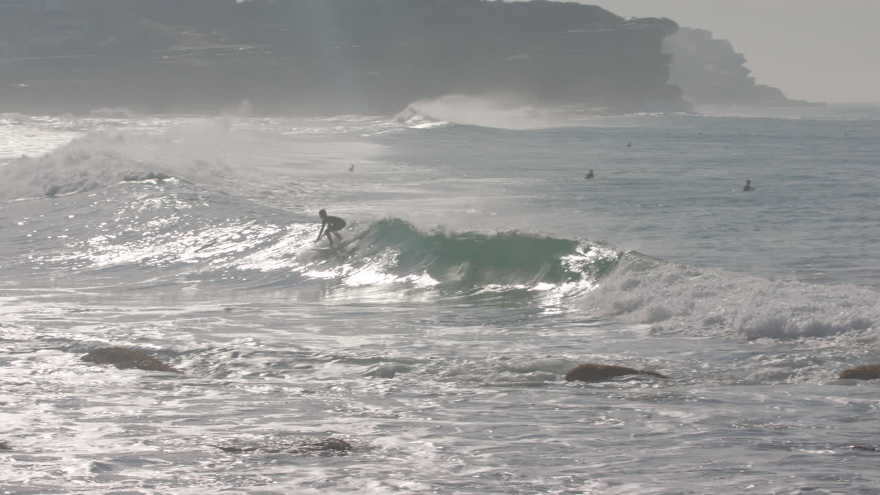 남자다운 비치 시드니 호주의 서사시 파도에 서퍼가 슬로우 모션으로 나타납니다.