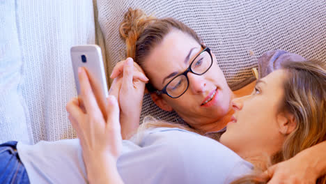 una pareja de lesbianas interactuando entre sí mientras usan un teléfono móvil 4k