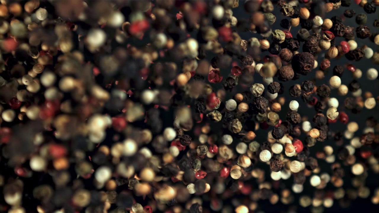 Grani di pepe misti che cadono in super slow motion