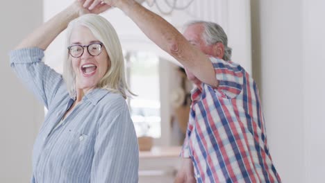 Feliz-Pareja-De-Ancianos-Caucásicos-Divirtiéndose-Bailando-Juntos-En-Casa,-Cámara-Lenta