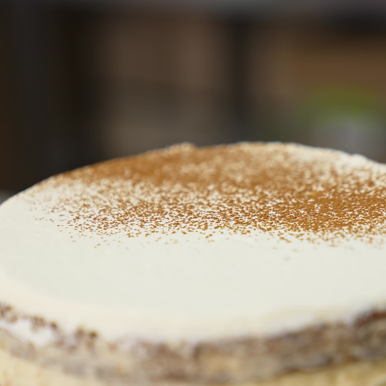 White creamy surface of the cake sprinkled with cacao powder. Close up. Decorating the cakes at modern confectionary