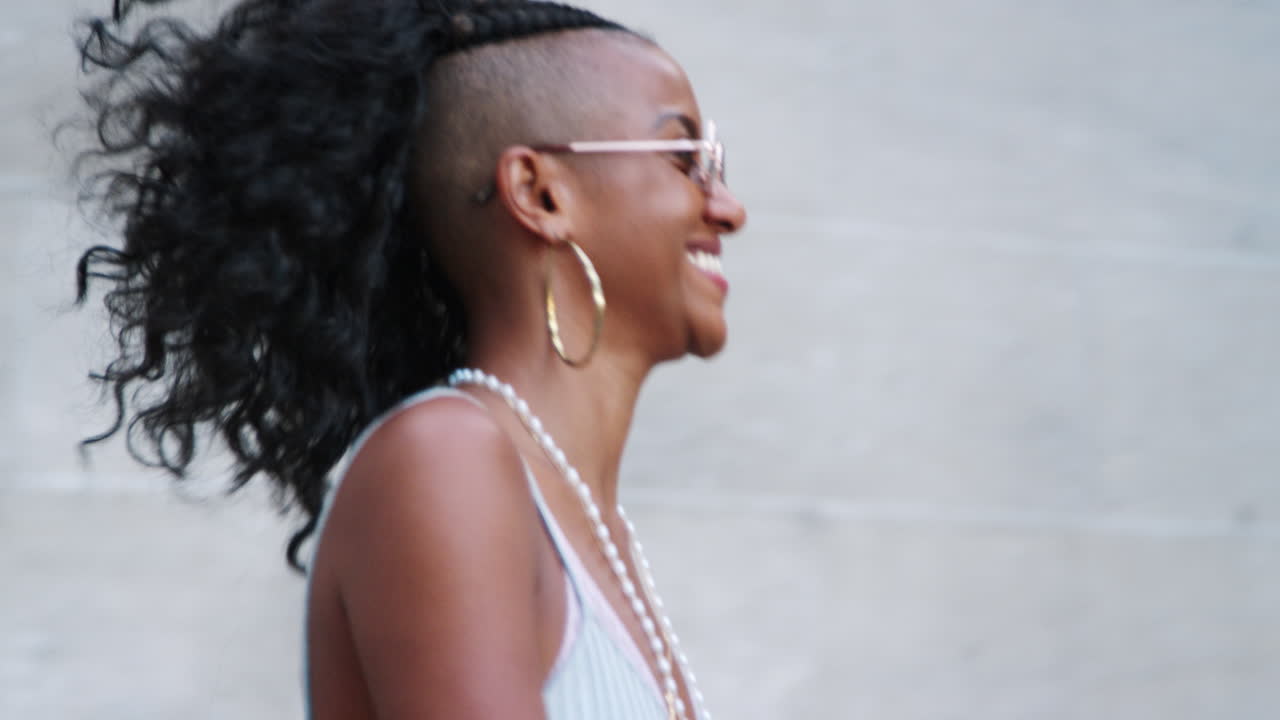 Fashionable young black woman wearing sunglasses walking down stairs in city street, close up