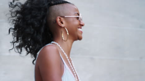 fashionable young black woman wearing sunglasses walking down stairs in city street, close up