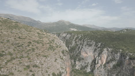 Drone-shot-near-Gjipe-beach-Albania-near-the-mountains-and-the-sea-on-a-sunny-and-bright-day-and-green-nature-around-in-between-rocks-gap-crack-massive-split-LOG