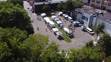 shoppers visit tents at a farmers' market in a parking lot