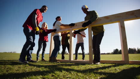 volunteers collaborate on outdoor wooden structure construction