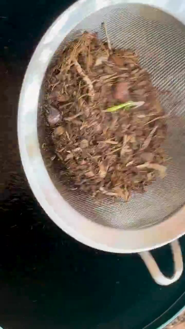Organic compost sifted with handheld mesh strainer, separating fine soil from debris outdoors in daylight