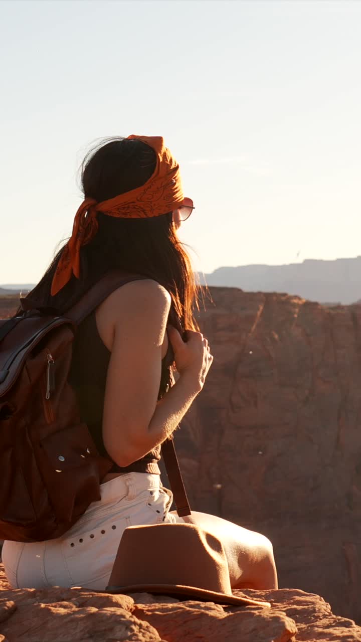 Escursionista donna seduta su una rupe che si affaccia su un canyon desertico