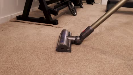 a vacuum cleaner moves across a carpeted gym floor, highlighting cleanliness and efficiency in a well-lit environment