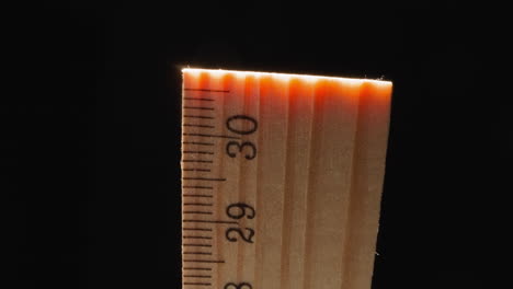 Orange-light-at-end-of-wooden-ruler-on-black-background