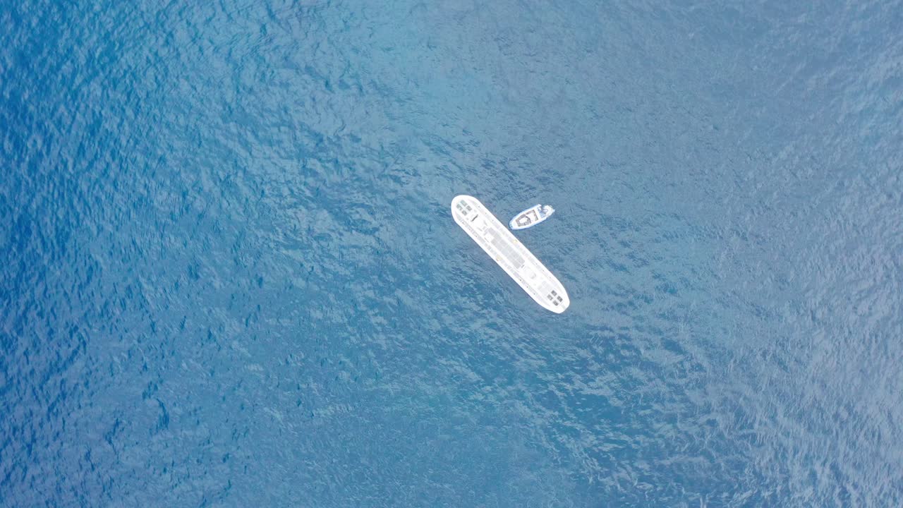 Panning bird's eye aerial shot looking down at a submarine in the open ocean off the coast of Kailua-Kona on the Big Island of Hawai'i