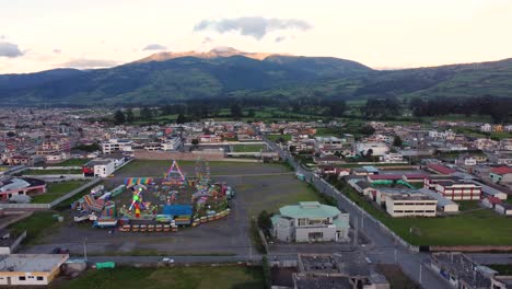 Clip-of-drone-flying-sideways-near-an-amusement-park-with-a-large-Ferris-wheel-near-a-town-in-Machachi,-Ecuador