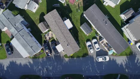 an aerial down looking view of a well kept mobile, manufactured, prefab home park of single wide and double wide houses on a sunny day