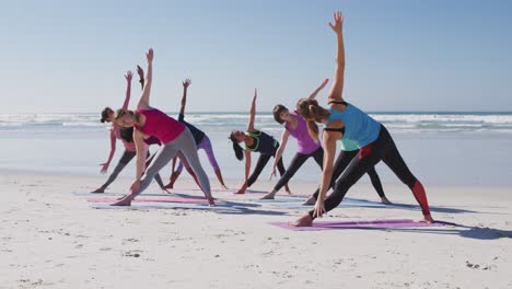 Multiethnische-Gruppe-Von-Frauen,-Die-Yoga-Position-Am-Strand-Und-Im-Hintergrund-Des-Blauen-Himmels-Machen