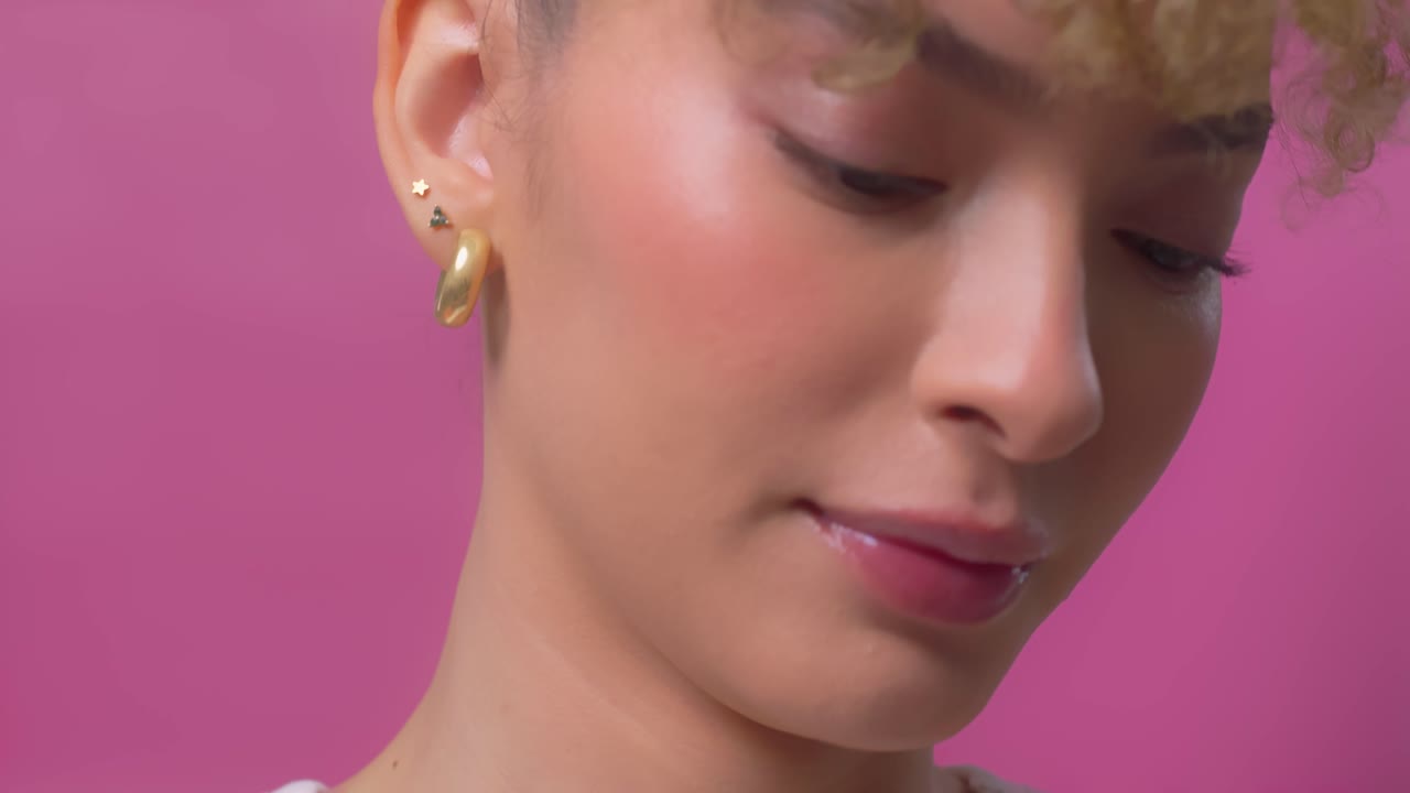 Slow motion close up of woman applying lip gloss with a sensual expression and soft lighting