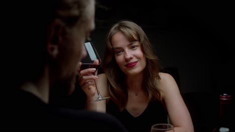 a man pours a glass of wine while a woman gazes at him seductively - close up