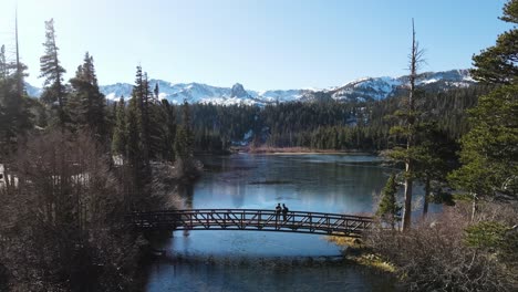 Drone-Backing-Up-From-Snowy-Mountains-Over-a-Bridge-in-Mammoth-Lakes-California