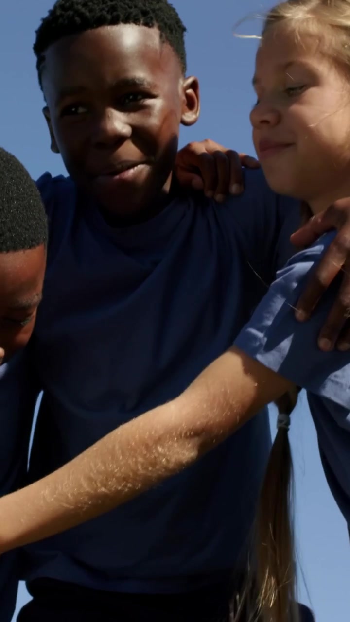 Vertical video: Hugging three students leaning together at schoolyard, showing braid and uniforms