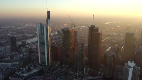 Establishing-Shot-of-Frankfurt-am-Main,-Germany-big-city-Skyline-and-Skyscraper-Buildings-in-Golden-Hour-Haze-with-Sun-rays,-Aerial-truck-slide-right