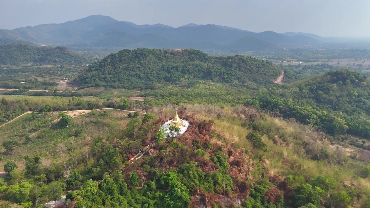 Ampio avvicinamento aereo su una pagoda dorata in cima a una collina presso il tempio Wat Pa Sawang Bun, che rivela un paesaggio montano rurale panoramico a Saraburi, Thailandia.