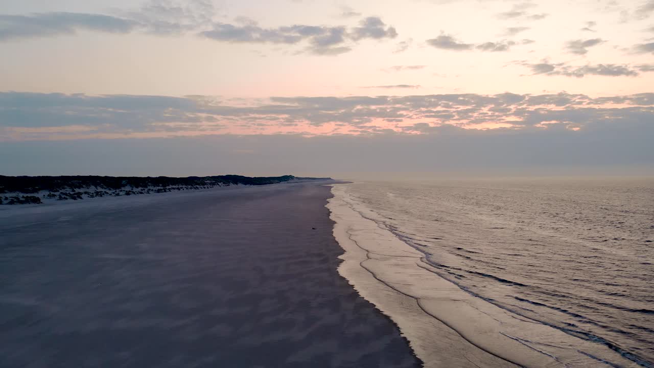 dron sobre olas tranquilas en la playa con tonalidad rosada desde el cielo al atardecer en la isla de langeoog, alemania