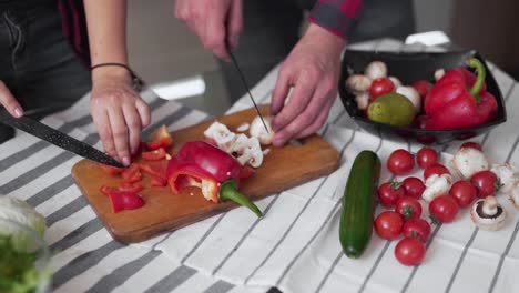 closeup-of-male-and-female-hands-slicing-vegetables