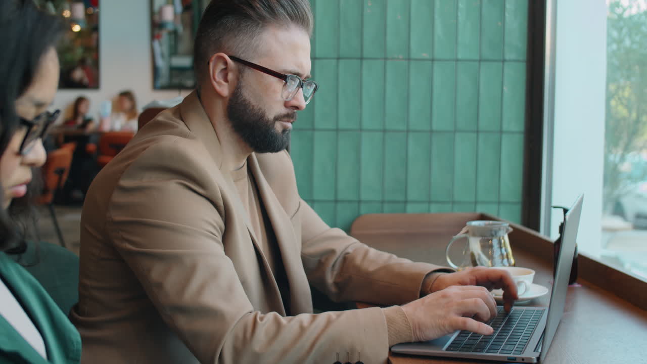 hombre de negocios escribiendo en una computadora portátil en un café