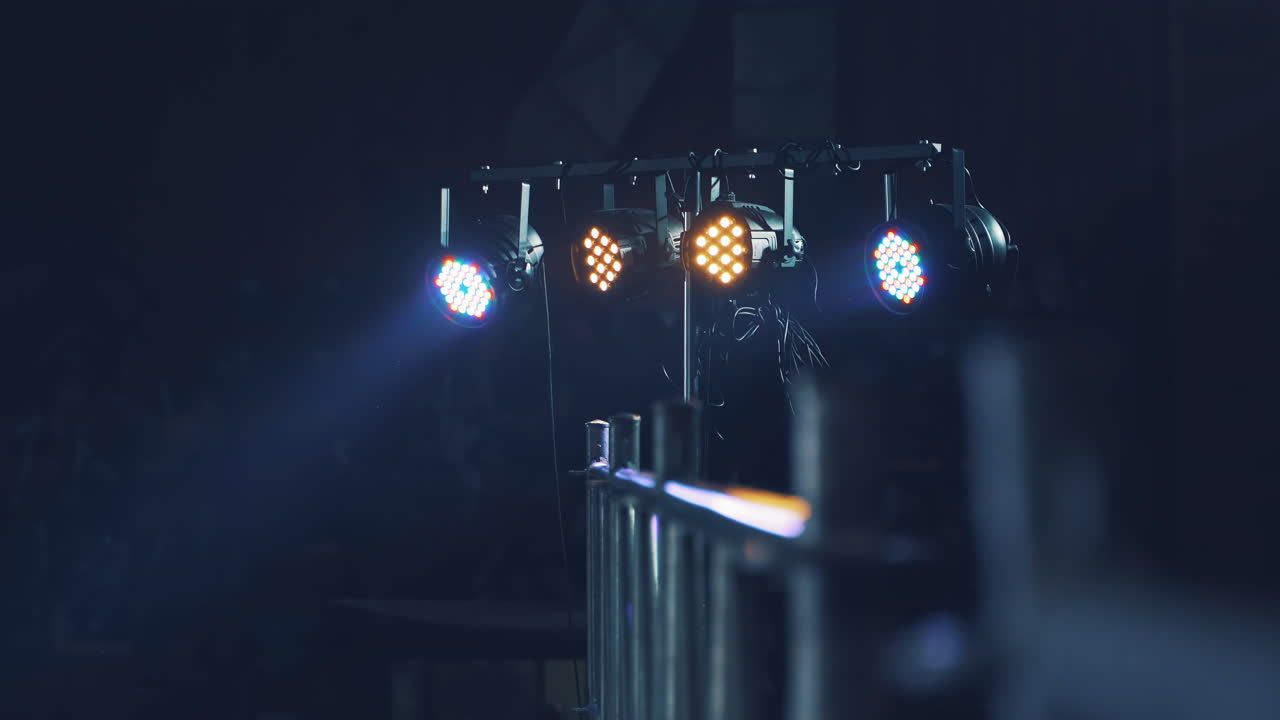 Bright lights from the projector shining from the scene on the blurred background. Projector lens lightning at disco on a special stand intdoors.