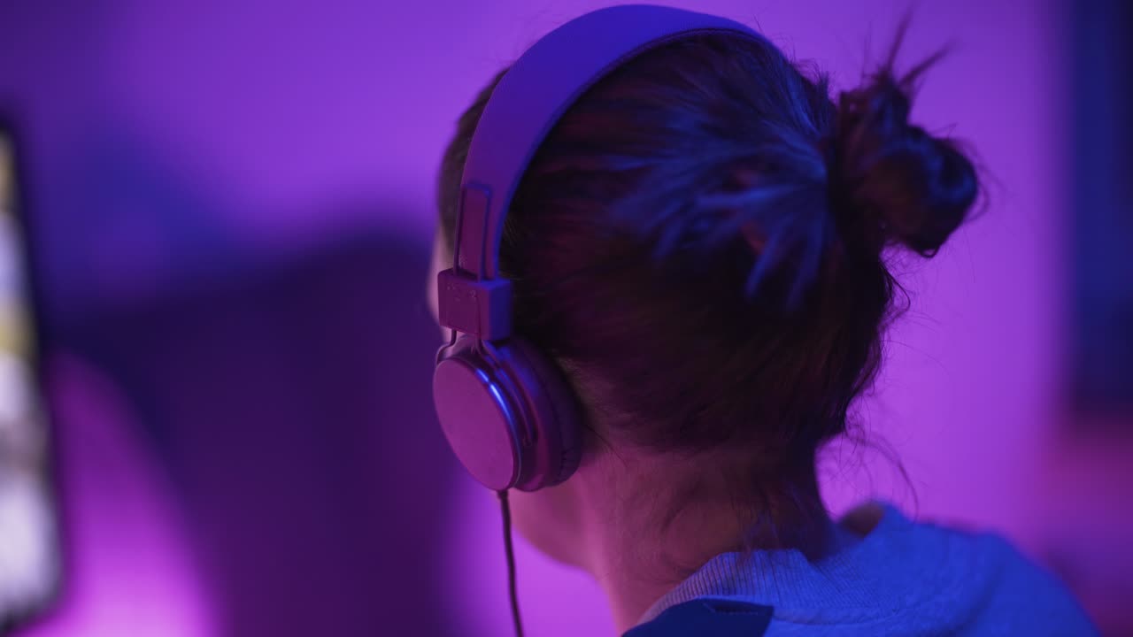 una foto de una jugadora profesional desde atrás a la izquierda jugando un videojuego en línea-3