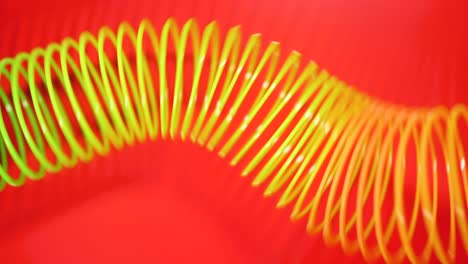 vintage retro abstract background. rainbow coloured spring moves across a red background in a wave like pattern. slinky toy. rainbow spiral spring motion wave a bright beautiful background.