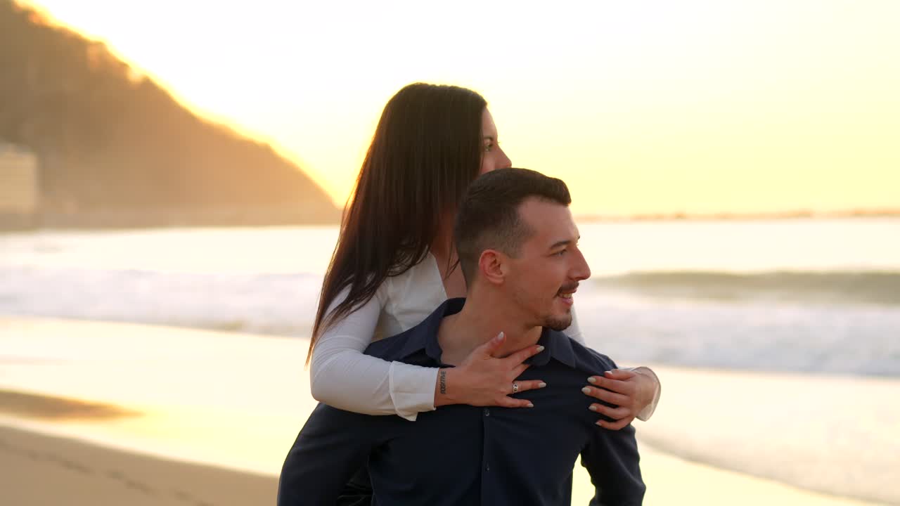 Couple enjoying piggyback ride on the beach at sunset