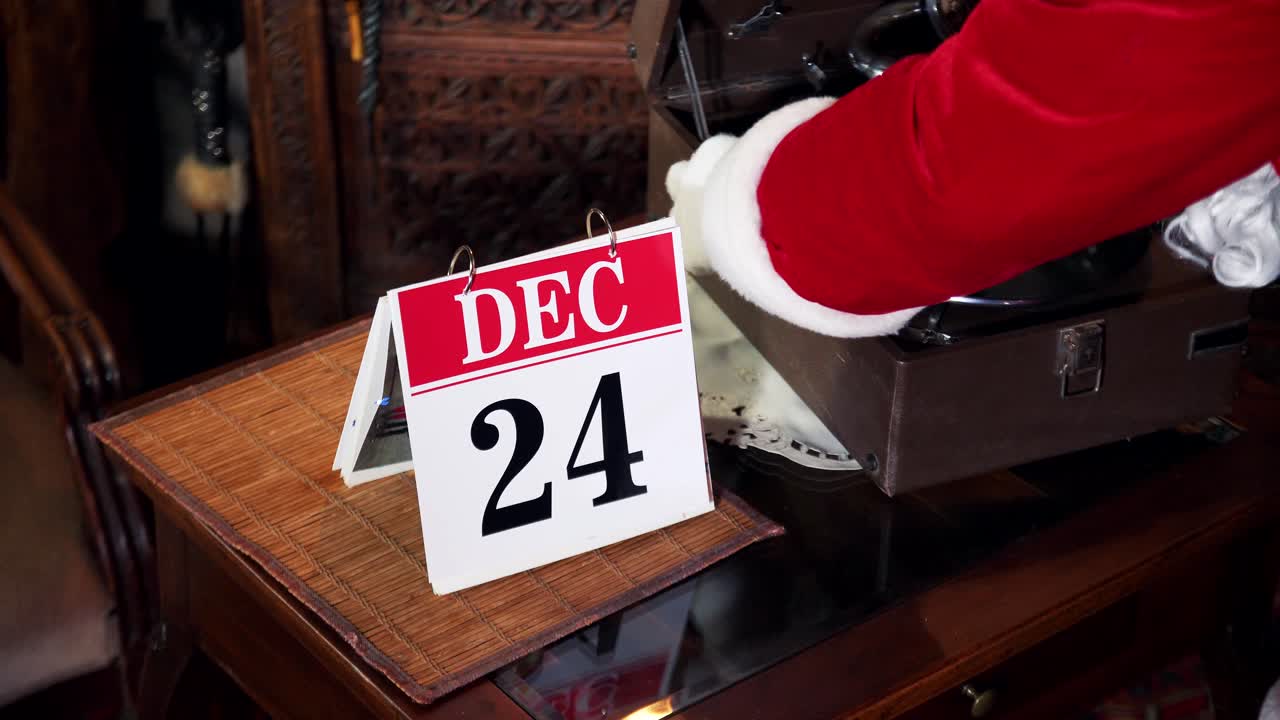 Santa's hands changes the calendar page into 24th of December. Santa Claus switches on the old recorder at xmas days
