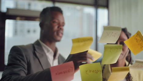 brainstorming in marketing department of big company african persons are sticking post-it notes