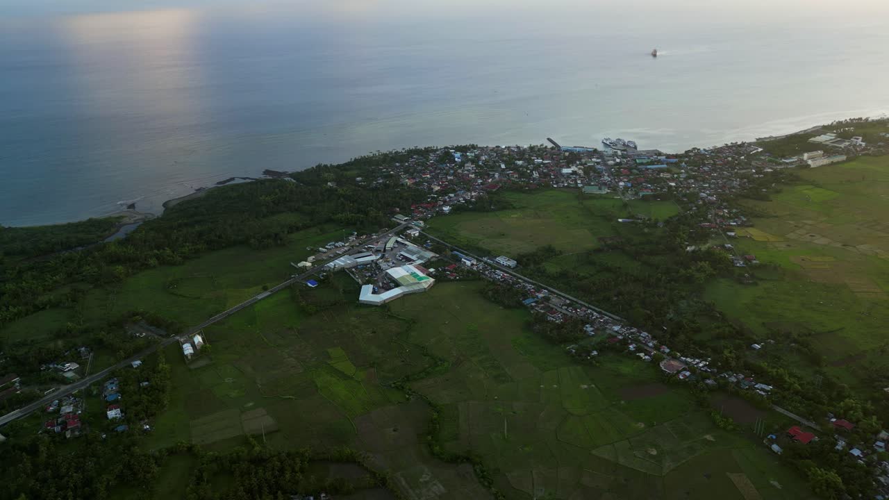 Panoramic aerial view of lush, rural barangay town along tropical island coastline at San Andres, Catanduanes, Bicol, Philippines.