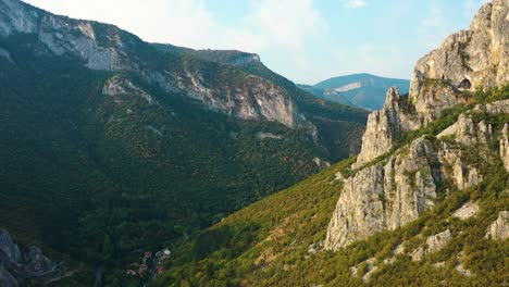 Cinematic-aerial-pan-mountain-rocky-peaks-in-distance,-autumn-forest