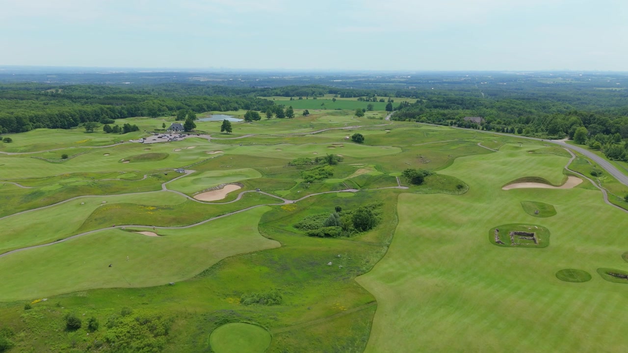Drone video soaring above Paintbrush Golf Course at the Pulpit Club in Caledon, Ontario, reveals sculpted fairways, sand bunkers, lush greens, and winding paths on a sunny day.