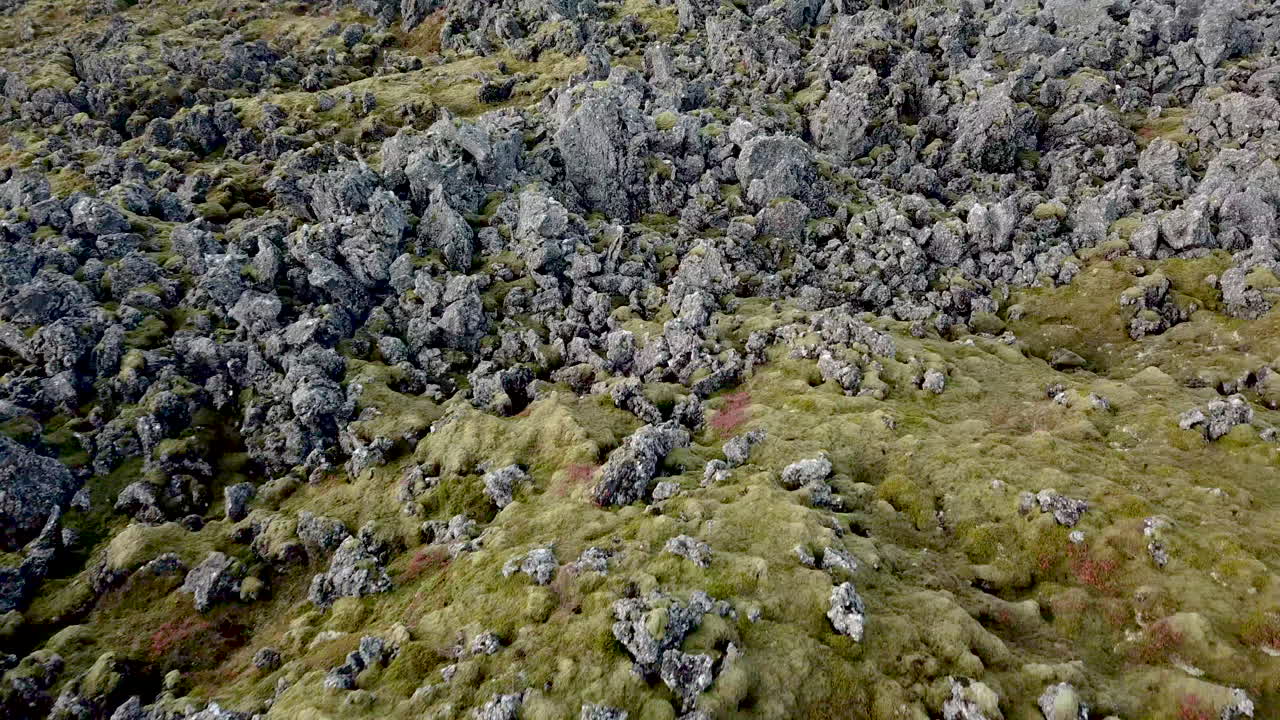 Aerial flight over lava fields then tilting up to reveal mountains