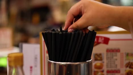 hand choosing chopsticks from a container