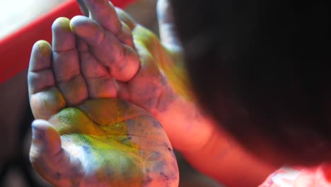 child's hands covered in colorful paint